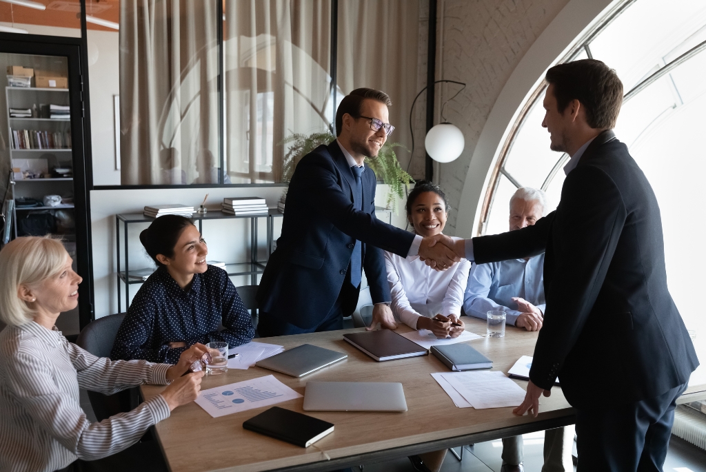 Man in contract role shaking hand of coworker in a friendly workplace culture