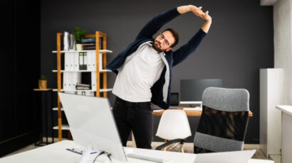 Man standing in home office stretching while looking at Flexible Staffing Strategies