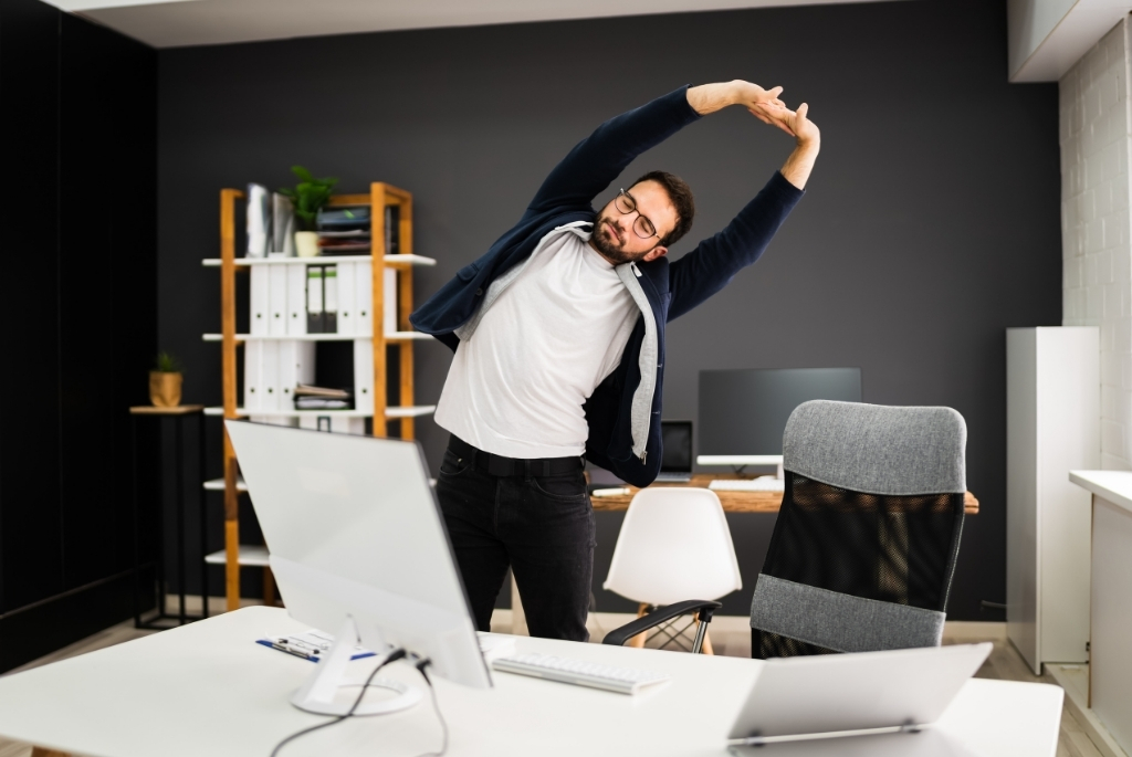 Man standing in home office stretching while looking at Flexible Staffing Strategies