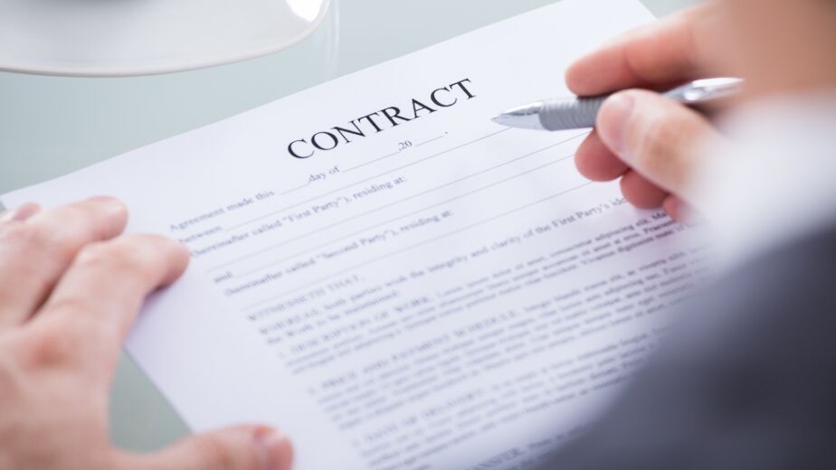 Hand and pen hovering over contract document for best contract jobs