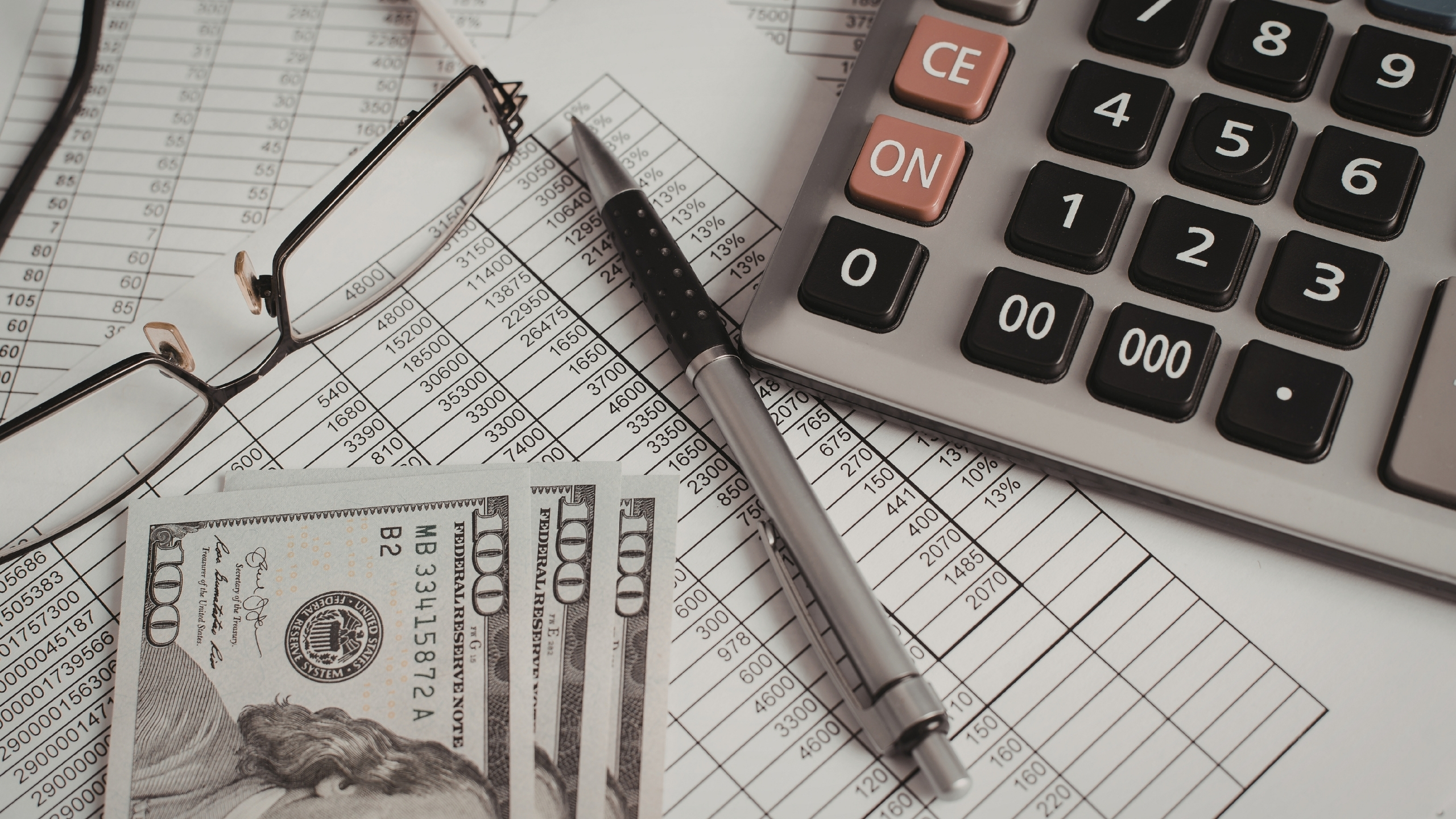 Money, calculator, pen and glasses laying on accounting documents