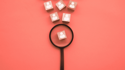 Magnifying glass hovering over wood block with person on it