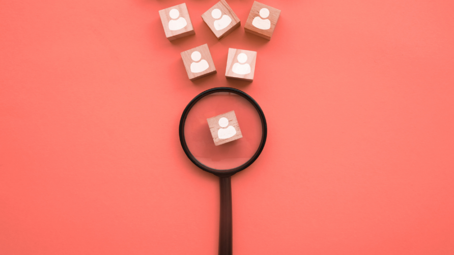 Magnifying glass hovering over wood block with person on it