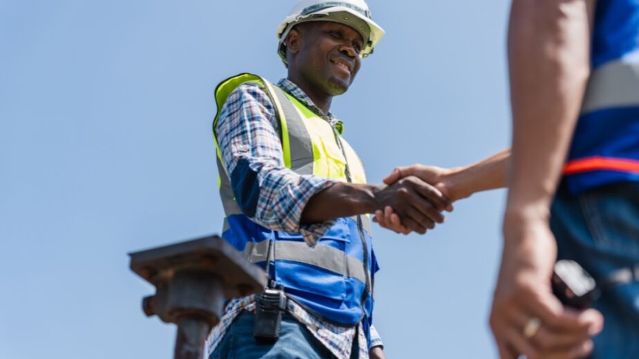 Two men in construction clothing shaking hands