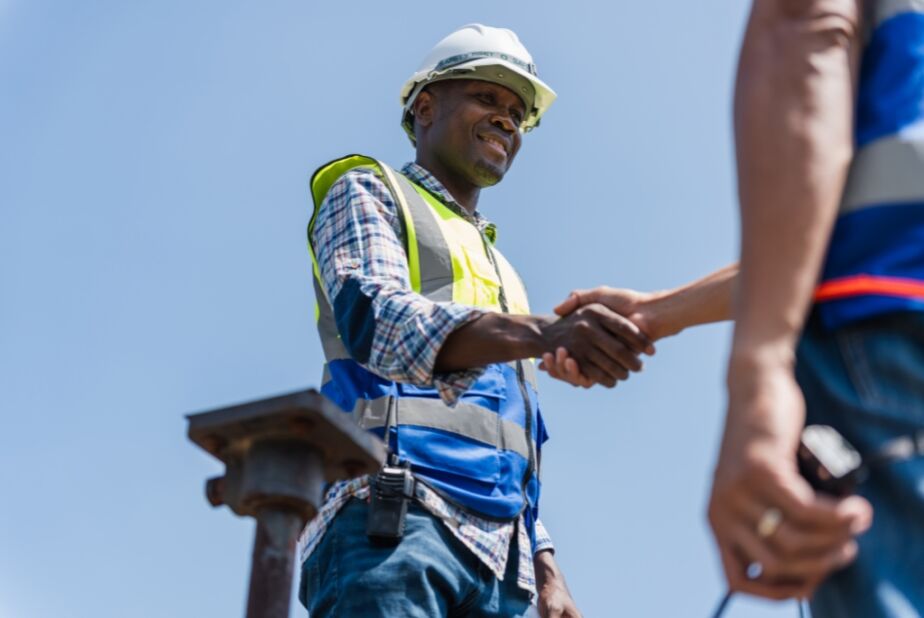 Two men in construction clothing shaking hands