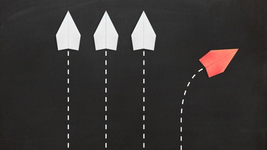 3 white paper airplanes going up, one red paper airplane going up and right