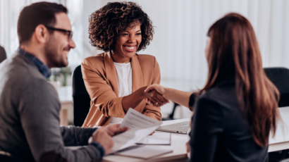 Woman shaking other woman's hand across a table to start behavioral interviewing process
