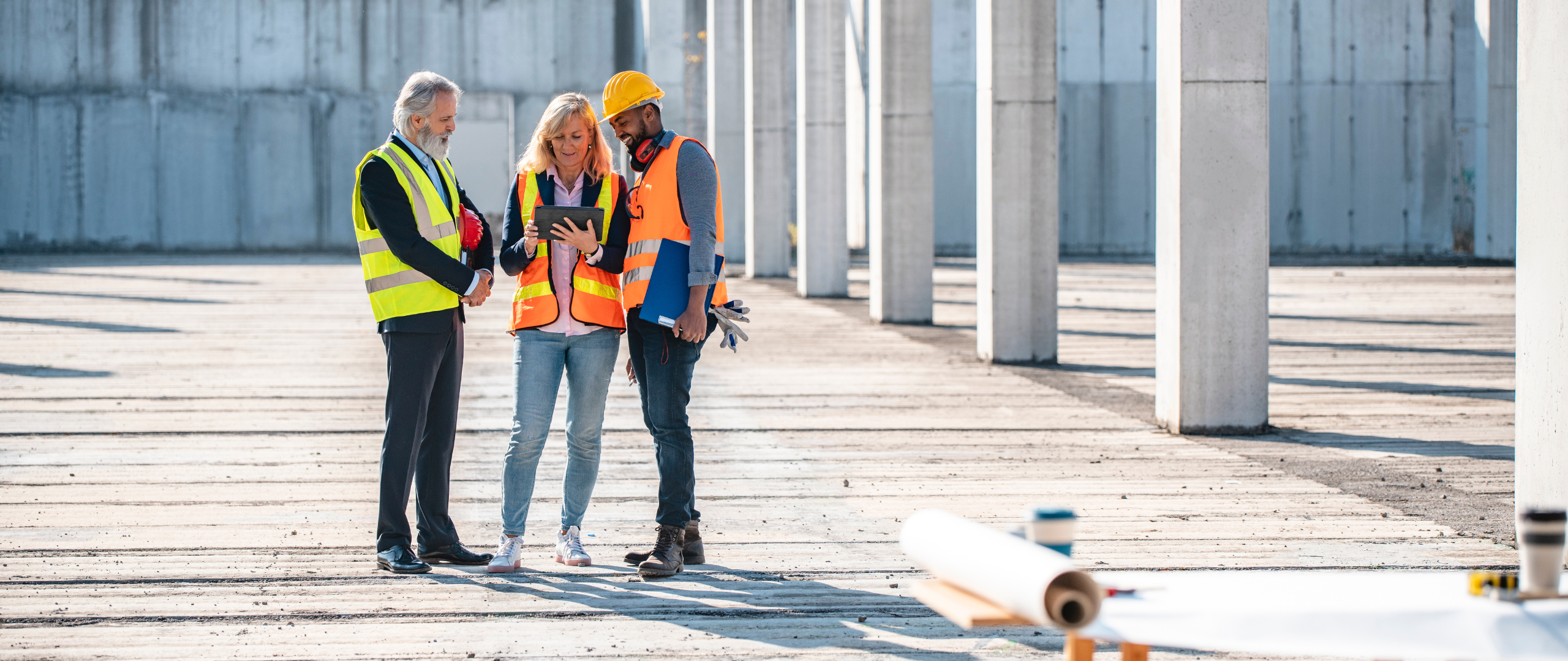 3 people huddled around tablet on construction site during project-based staffing work