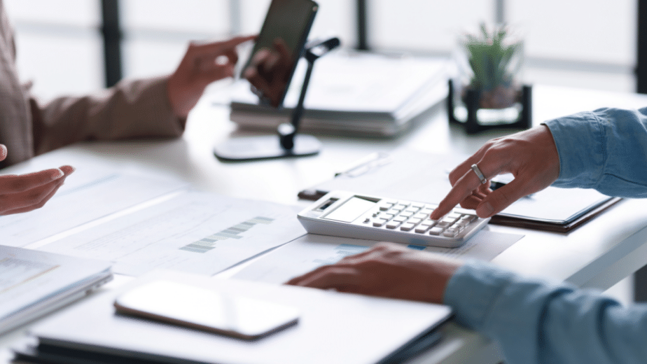 Banking compliance contractor type on calculator at desk