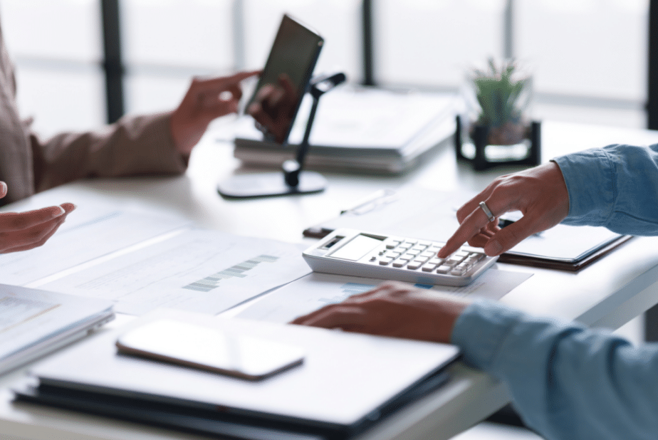 Banking compliance contractor type on calculator at desk