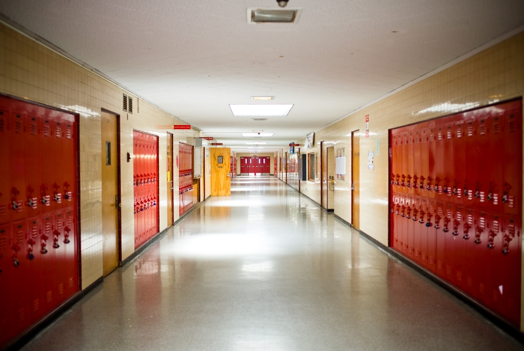 Empty school hallway with red lockers waiting for seasonal contract work to begin