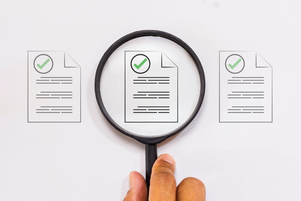 Magnifying glass hovering over compliance risk document for CHIPS, IRA, IIJA projects