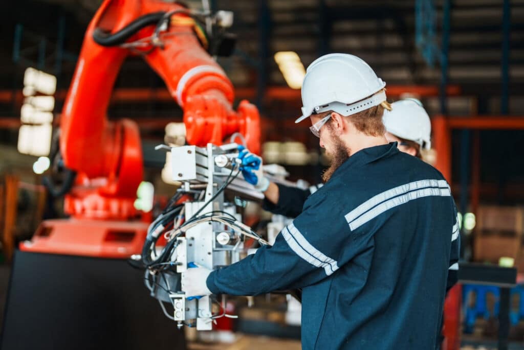 Man working on robotic arm to help with advanced manufacturing and automation setup